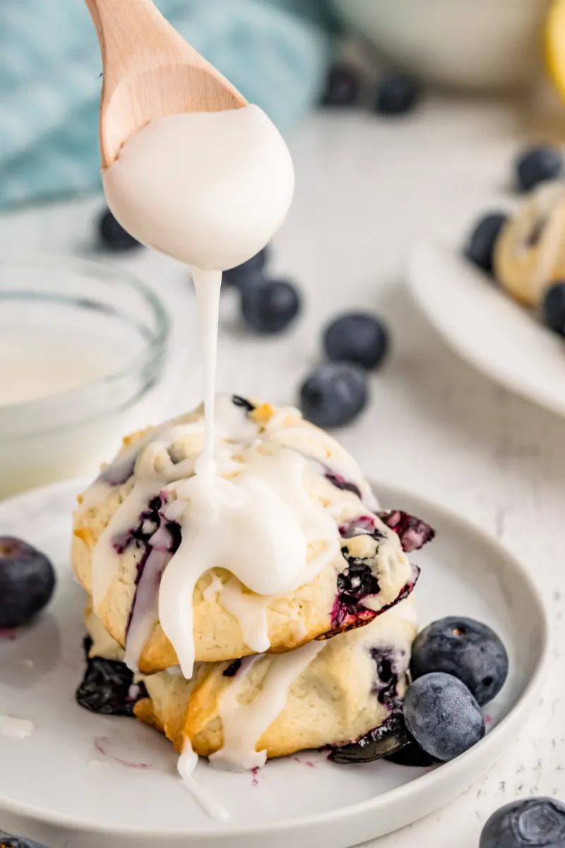 spooning icing onto blueberry cookies