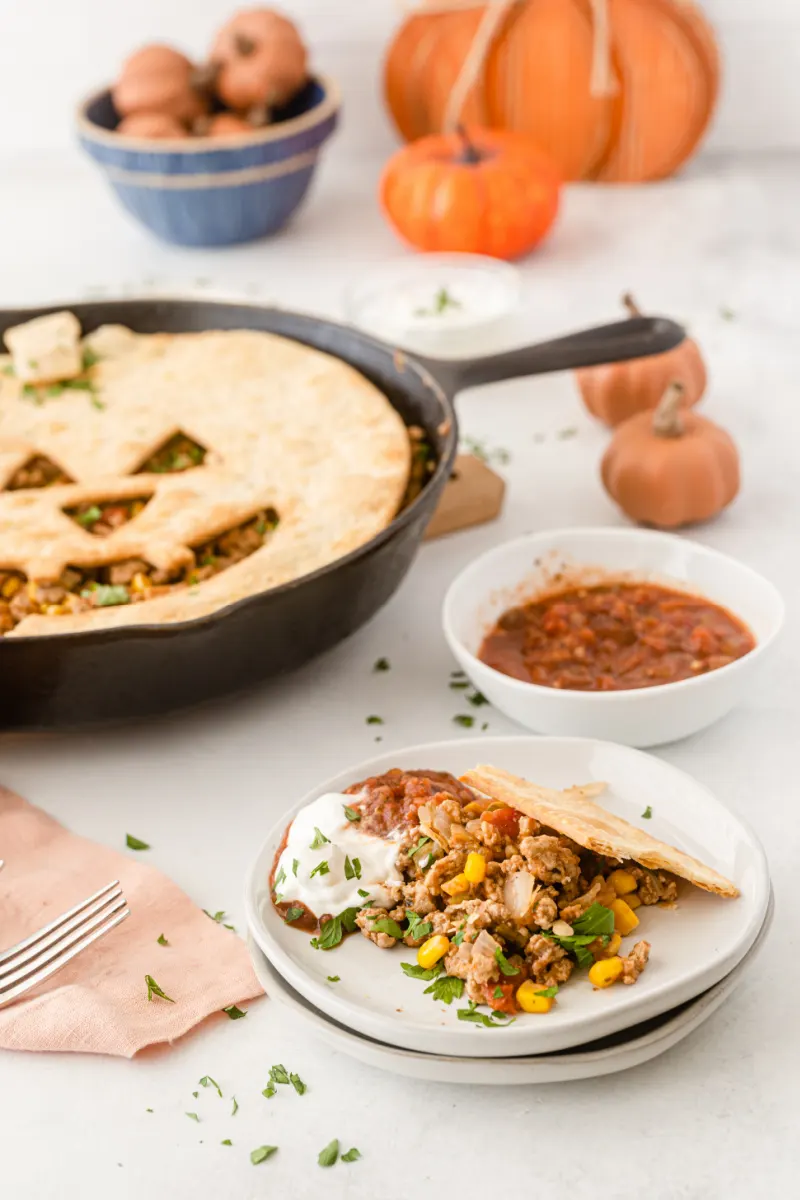 serving of sloppy joe pie on a plate with skillet of pie in background