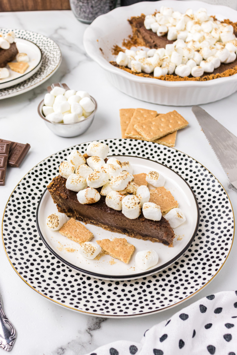 Slice of S'Mores Pie on a plate with rest of pie in background