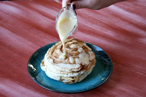 Adding glaze to Maple Cinnamon Roll Pancakes