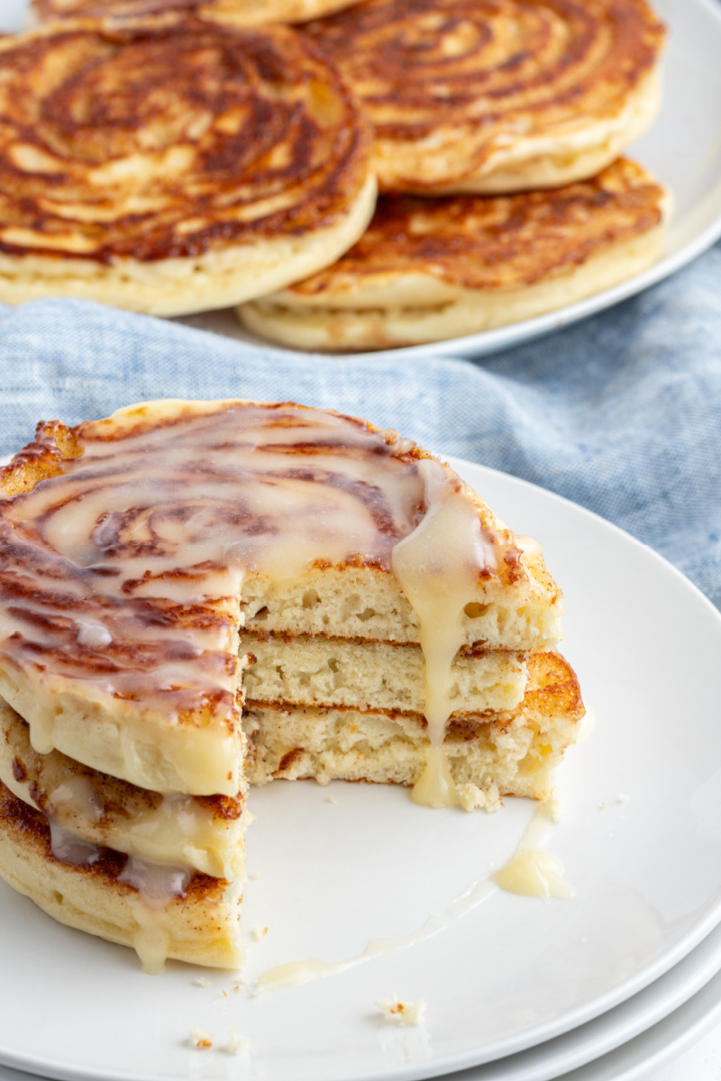 maple cinnamon roll pancakes on a plate with a large piece taken out