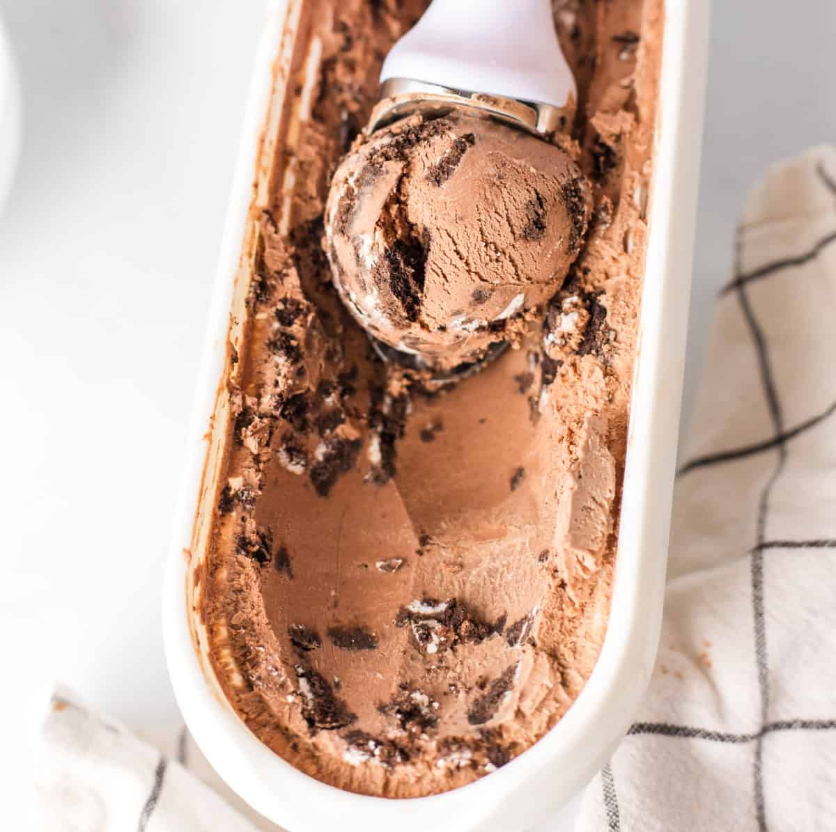 Chocolate cookies and cream ice cream made with a rich cocoa base and loaded with Oreo cookies. Creamy, indulgent and so good! scooping chocolate cookies and cream ice cream out of tub