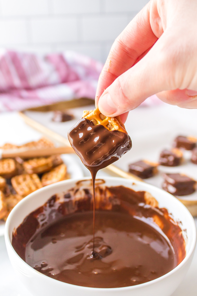 dipping a peanut butter pretzel into chocolate