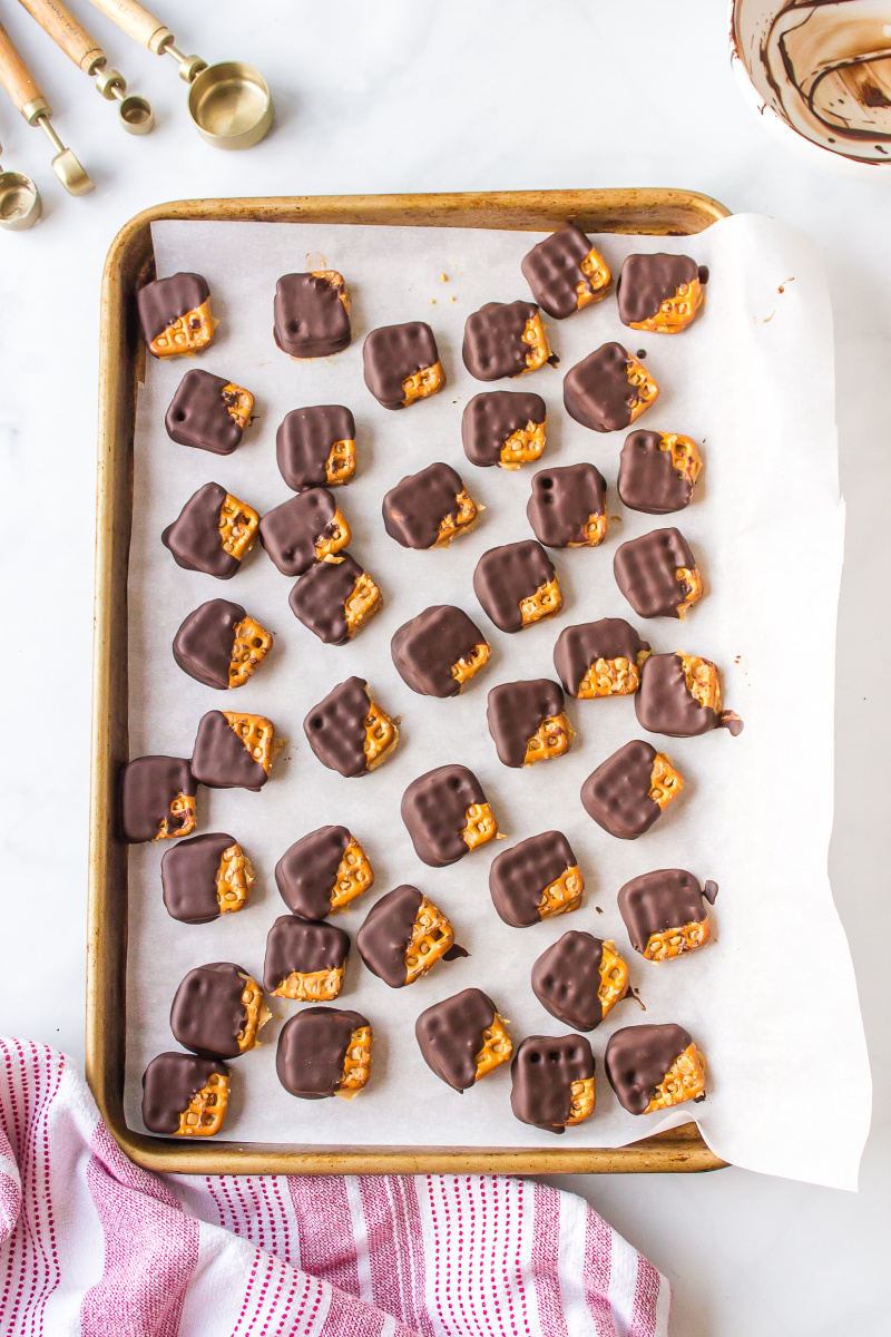 chocolate covered peanut butter pretzels cooling on baking sheet