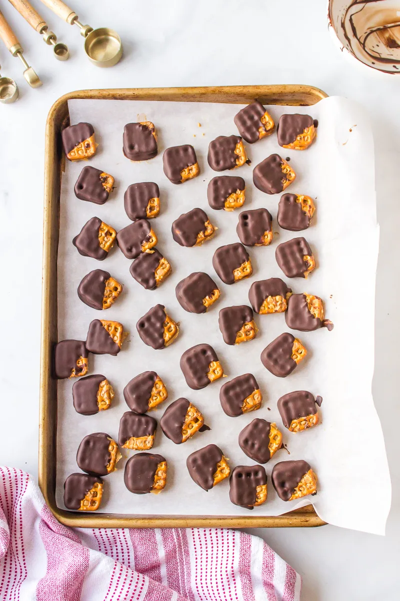 chocolate covered peanut butter pretzels cooling on baking sheet
