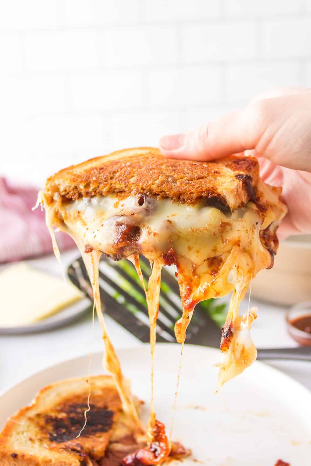Barbecue Bacon Grilled Cheese Sandwich recipe from RecipeBoy.com : barbecue grilled cheese : bacon grilled cheese : BBQ Grilled Cheese hand picking up half of barbecue bacon grilled cheese sandwich with cheese pull