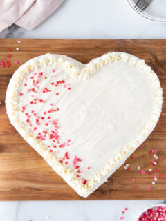 heart shaped cake with white frosting and pink sprinkles