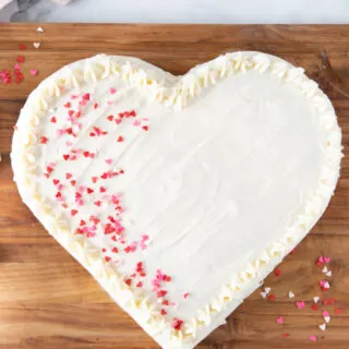 heart shaped cake with white frosting and pink sprinkles