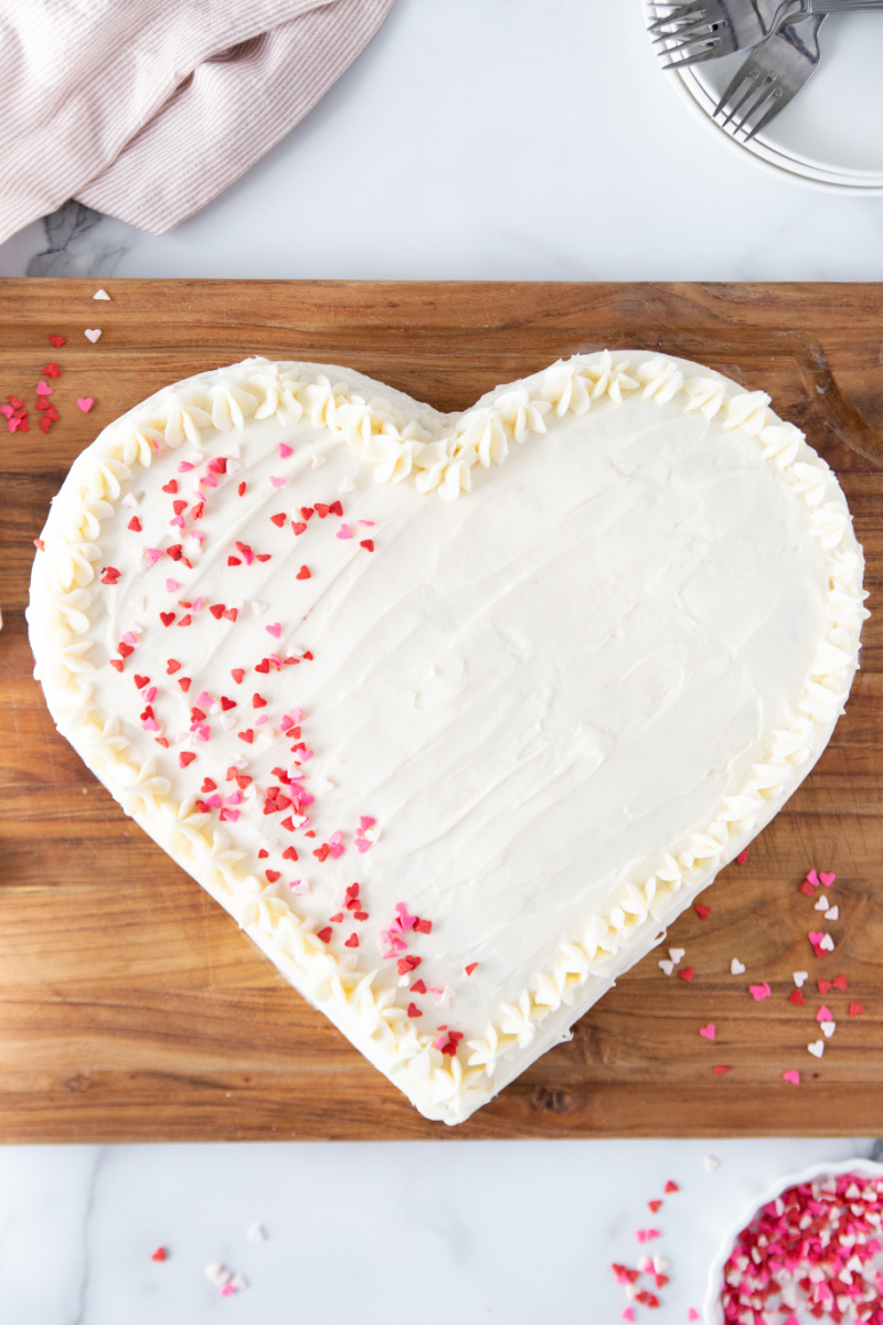 heart shaped cake with white frosting and pink sprinkles