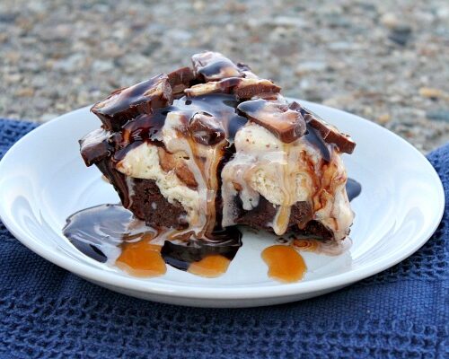 slice of snickers ice cream brownie pie on a white plate