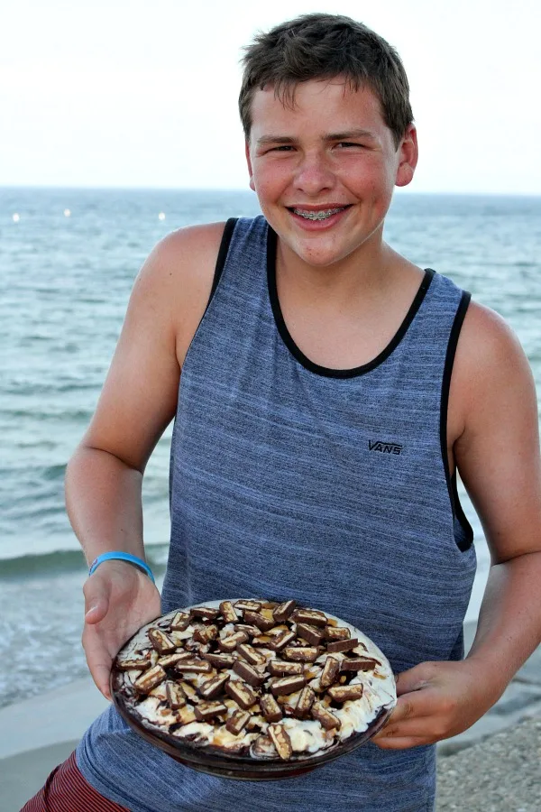 RecipeBoy at the beach holding Snickers Ice Cream Brownie Pie 