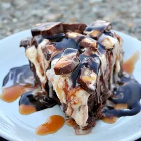 slice of snickers ice cream brownie pie on a white plate