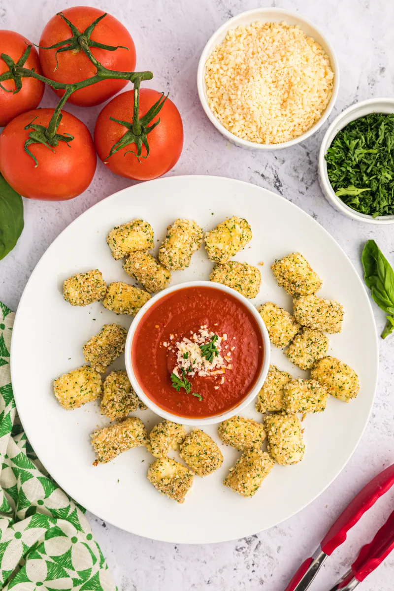 plate of baked mozzarella bites with bowl of red sauce in middle