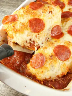 using a spatula to serve chicken pizzaiola from a white casserole dish