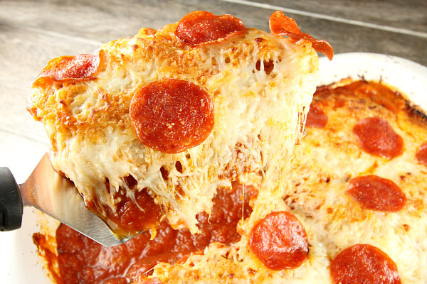 using spatula to serve chicken pizzaiola in a white casserole dish