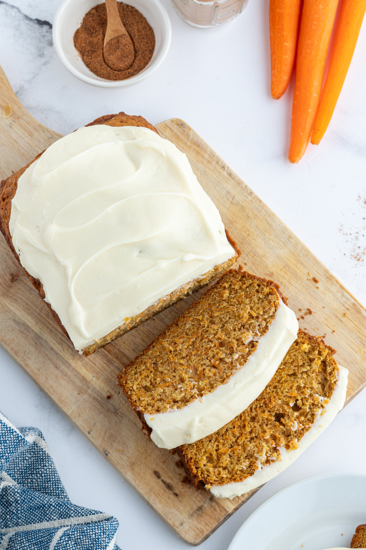 overhead shot of frosted carrot loaf cake partially cut into slices