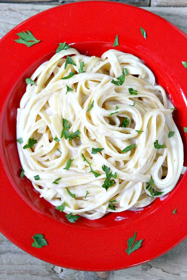 Best Alfredo Sauce Recipe mixed with hot pasta in a red dish