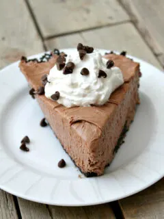 slice of nutella pie with whipped cream and chocolate chips served on a white plate on a wooden board