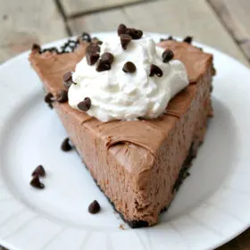 slice of nutella pie with whipped cream and chocolate chips served on a white plate on a wooden board