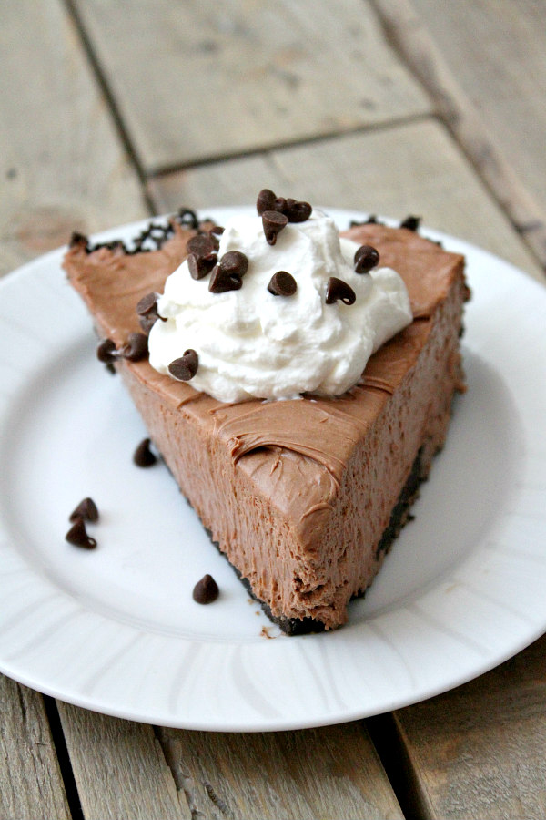 slice of nutella pie with whipped cream and chocolate chips served on a white plate on a wooden board