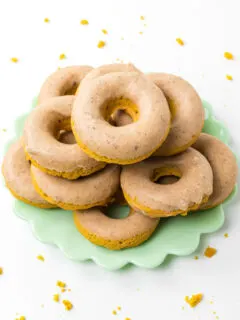 baked pumpkin donuts stacked on a green platter