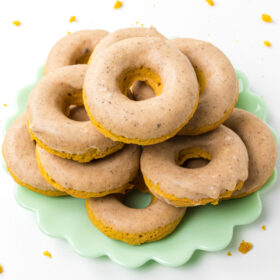 baked pumpkin donuts stacked on a green platter