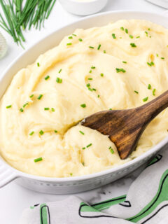 casserole dish with slow cooker mashed potatoes in it and a spoon