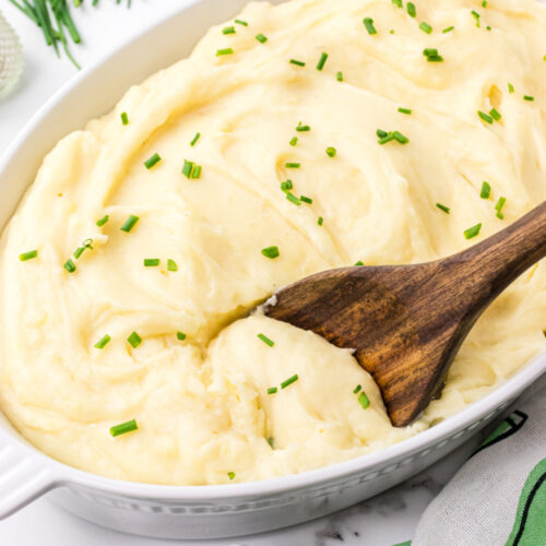 casserole dish with slow cooker mashed potatoes in it and a spoon