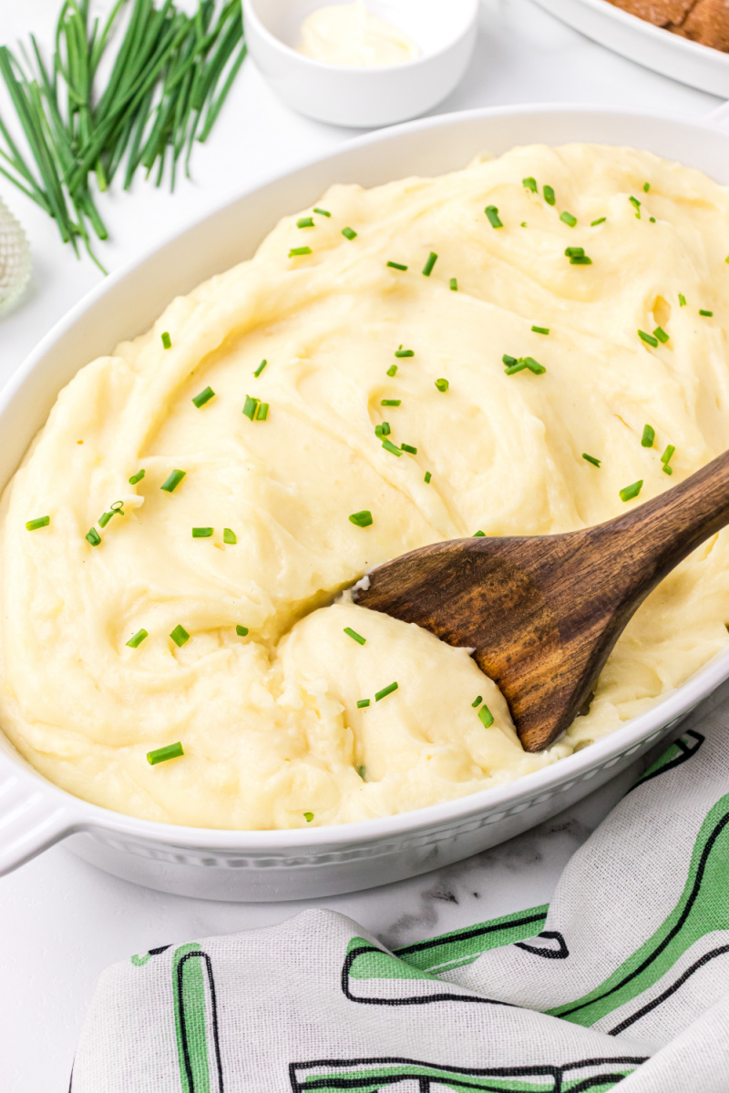 casserole dish with slow cooker mashed potatoes in it and a spoon