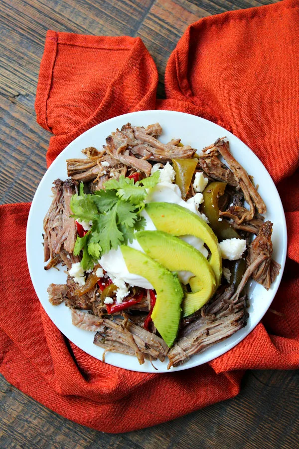 Slow Cooker Steak Fajitas topped with bell peppers, sour cream and avocado