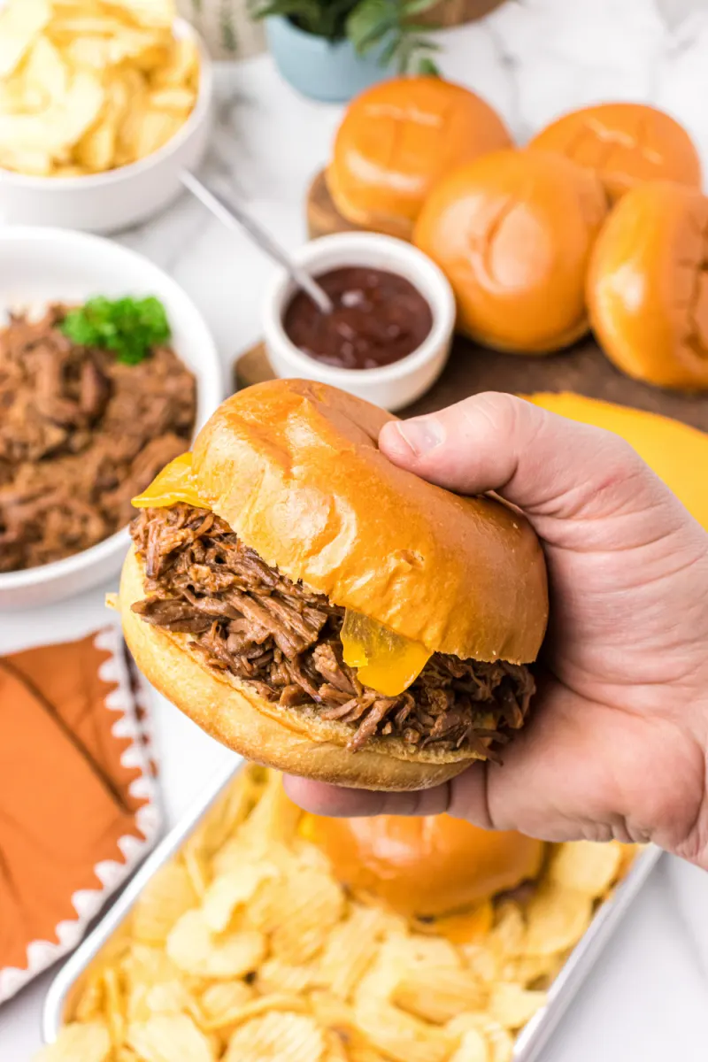 hand holding shredded beef sandwich