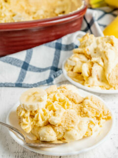 serving of banana pudding on a white plate with a blue plain cloth napkin