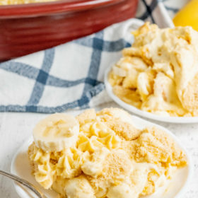 serving of banana pudding on a white plate with a blue plain cloth napkin