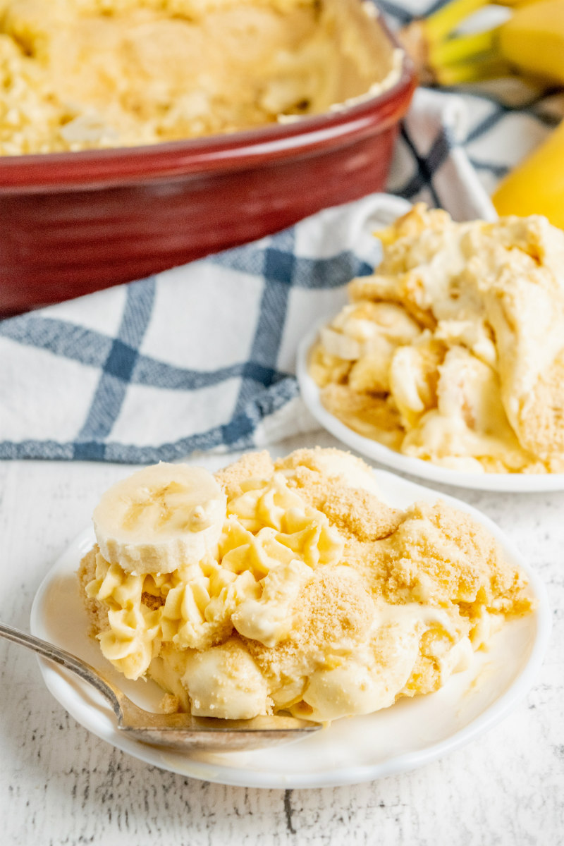 serving of banana pudding on a white plate with a blue plain cloth napkin