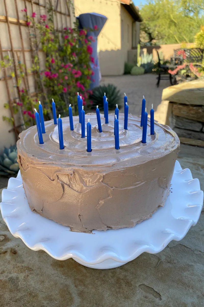 chocolate birthday cake with candles on a white cake platter