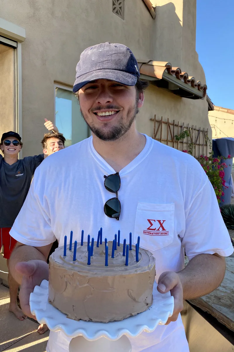 man holding a chocolate cake with candles.