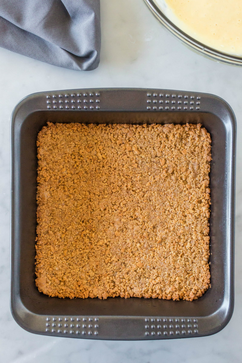 overhead shot of graham cracker crust in a square metal pan
