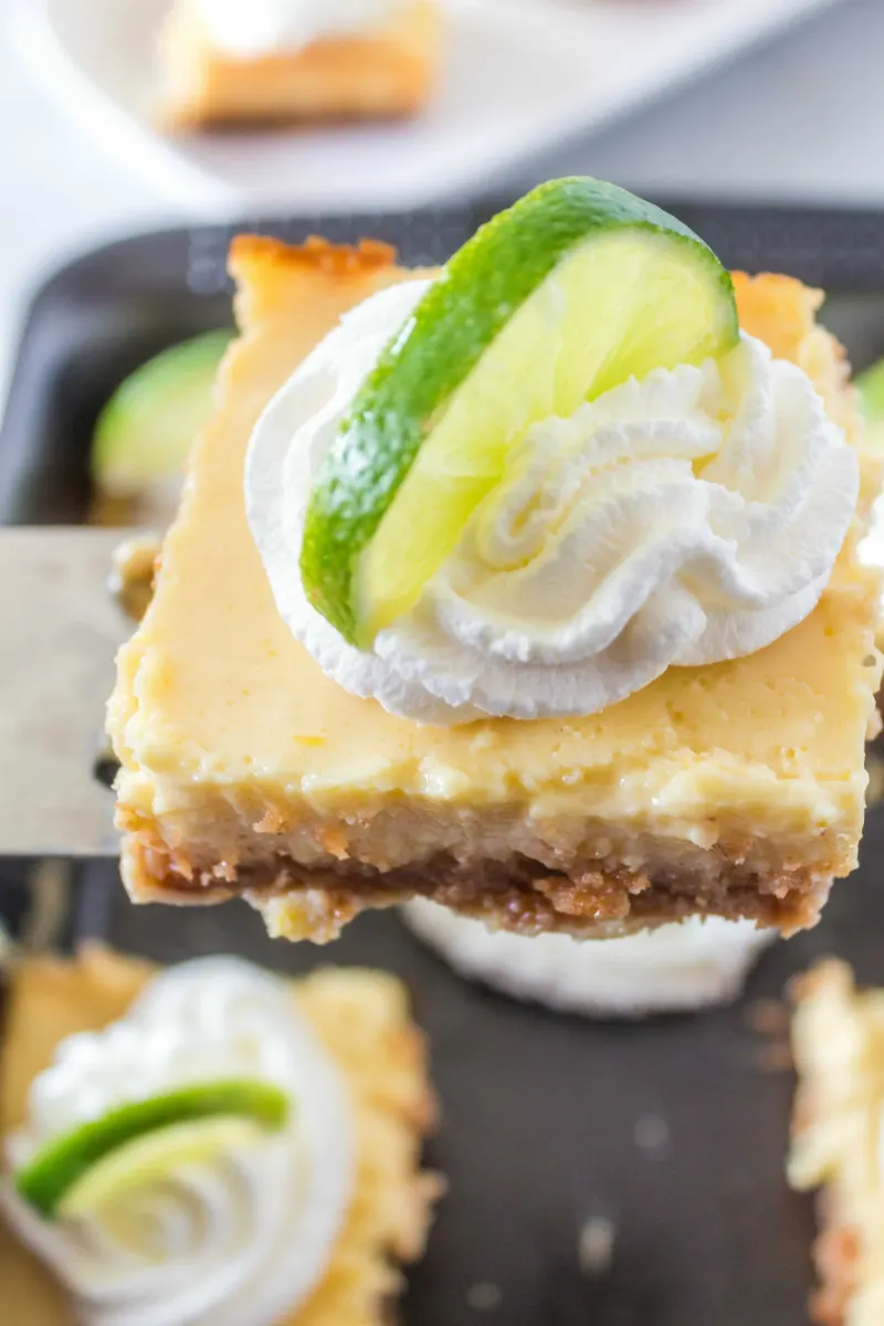 serving of key lime bars garnished with whipped cream and lime wedge