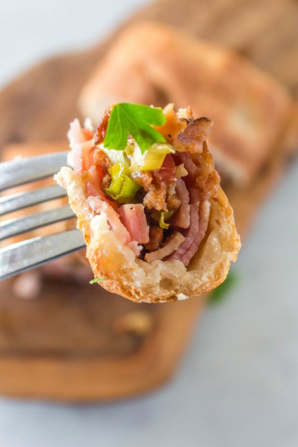 A bite with a fork of Ham and Swiss Stromboli