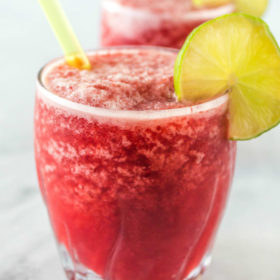 three cherry lime slushies garnished with lime and with a straw