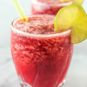 three cherry lime slushies garnished with lime and with a straw