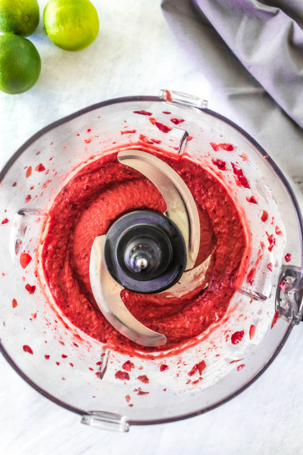 overhead shot of cherry lime slushies blended in food processor. fresh limes in the background