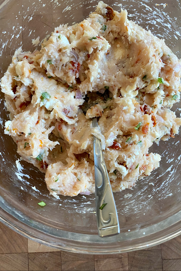 glass bowl with ingredients for chicken and sun dried tomato burgers mixed together