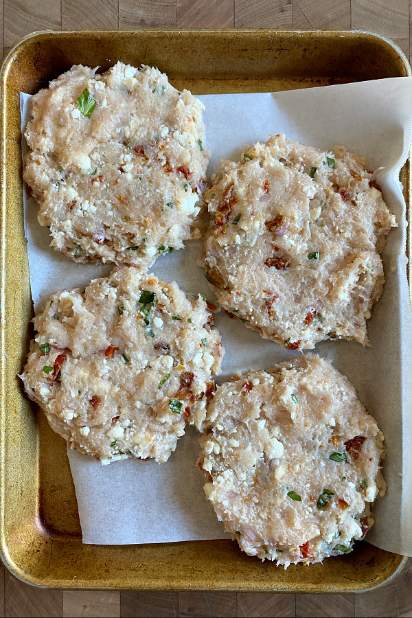 chicken and sun dried tomato burgers formed into patties and set on a baking sheet