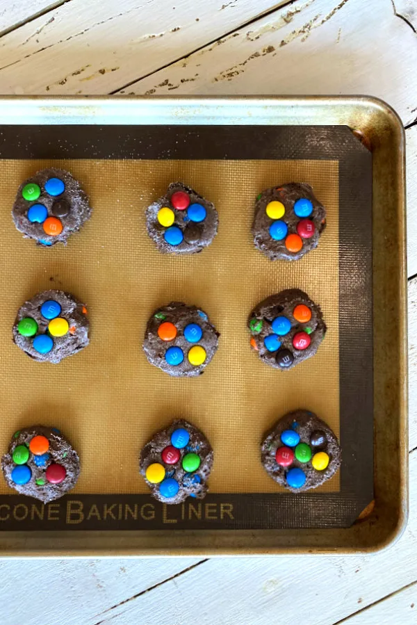chocolate cake mix m&M cookies on a silpat lined baking sheet ready for the oven