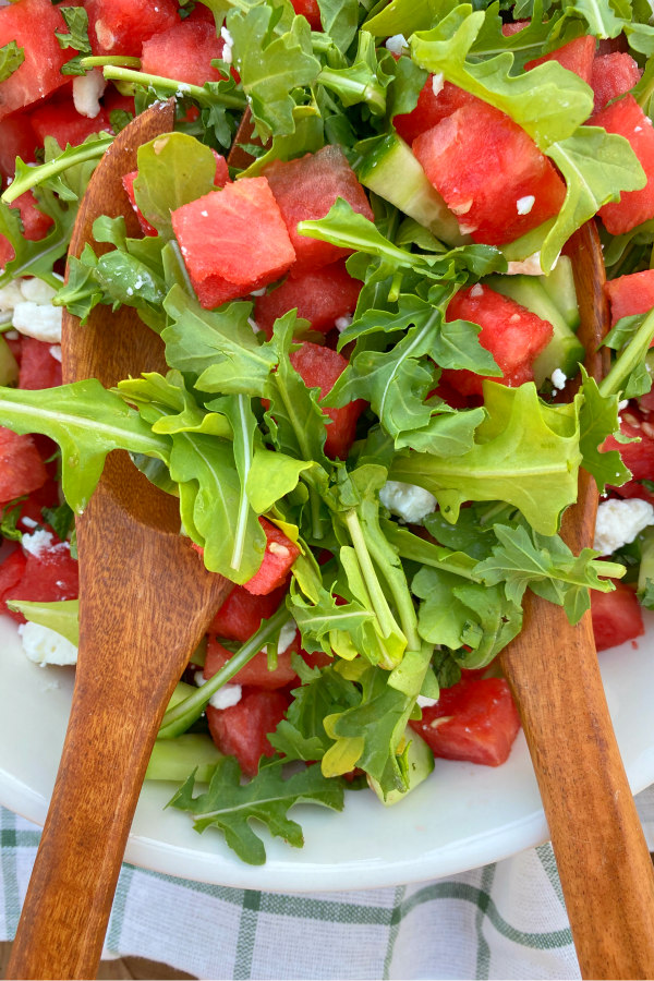 wooden serving spoons serving watermelon green salad