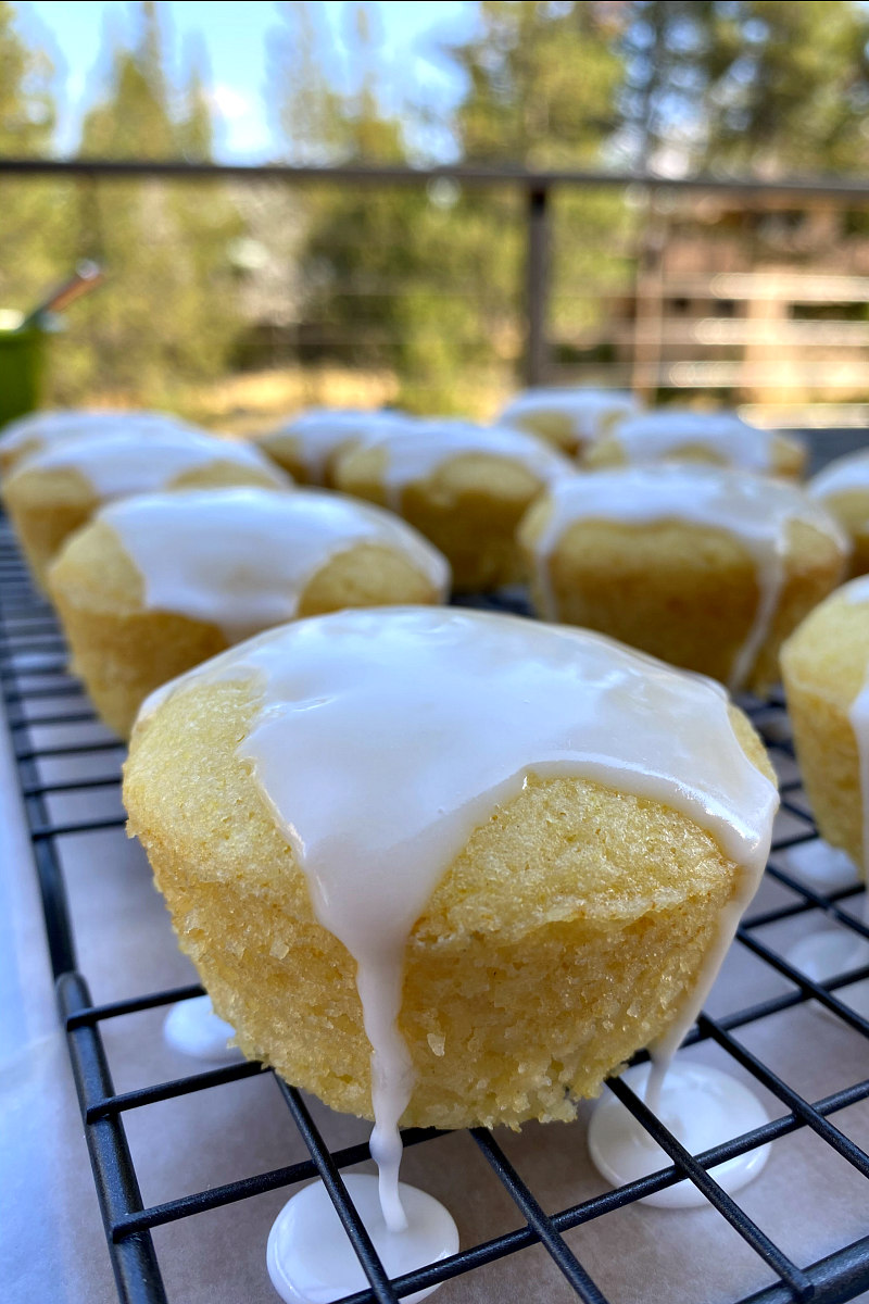 glazed lemon muffins on a rack with the glaze drizzling down the sides of the muffins