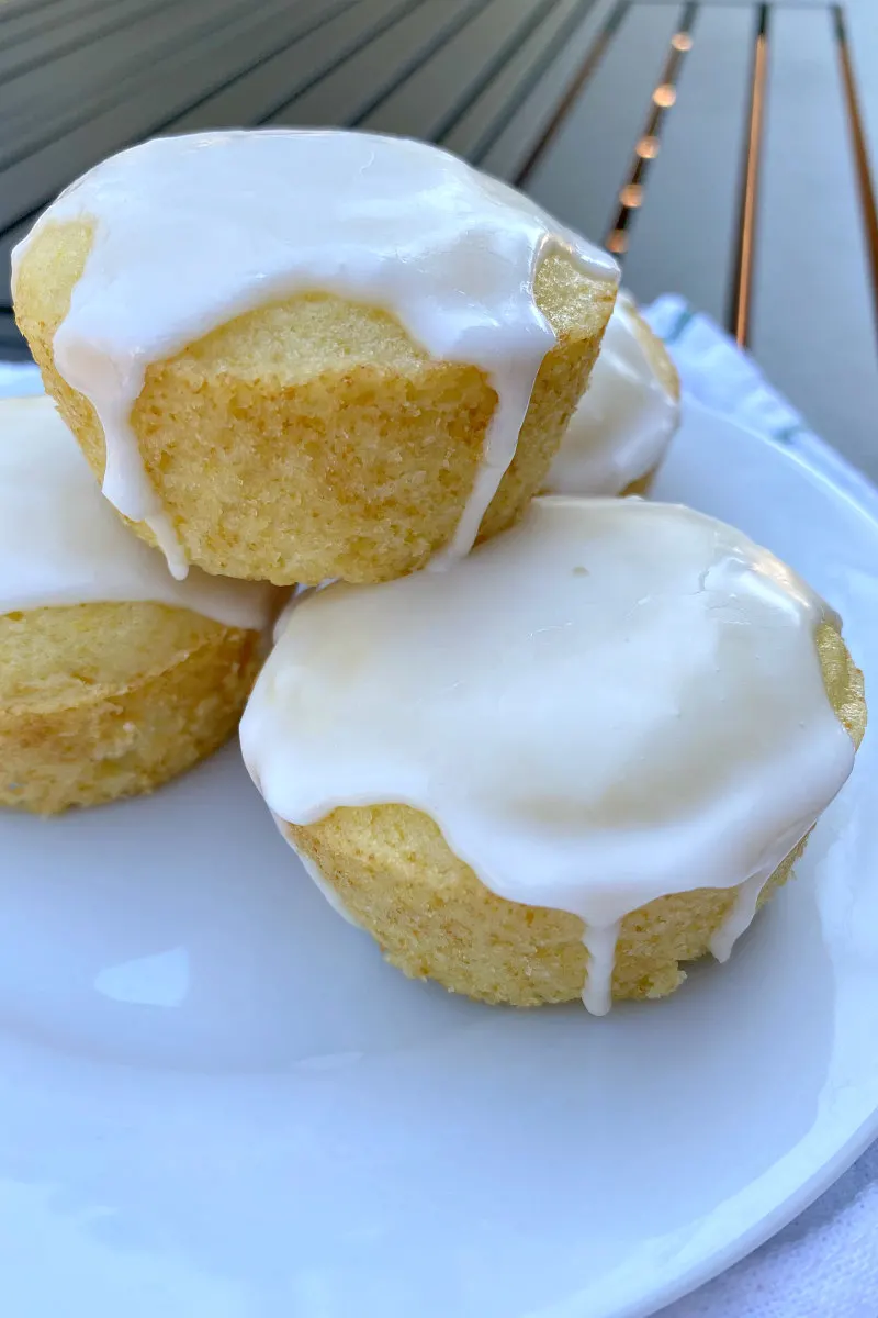 pile of three glazed lemon muffins displayed on a white plate