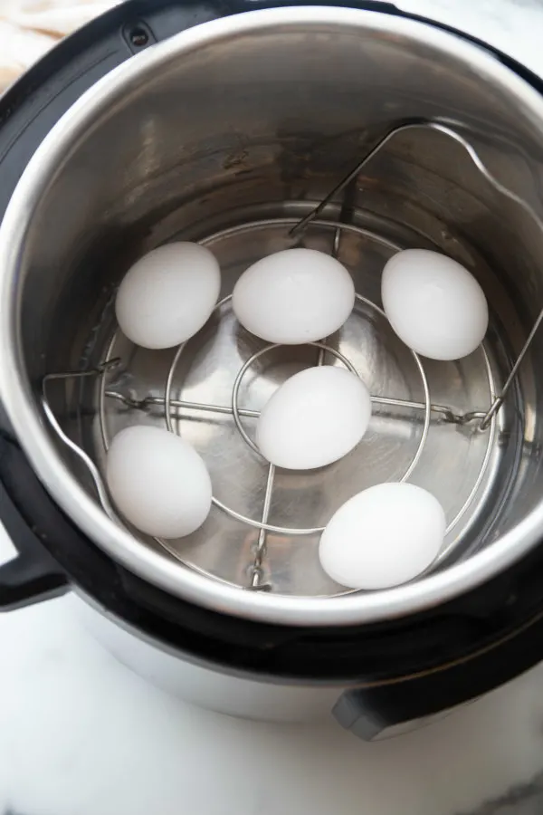 six hard boiled eggs sitting on the insert of an instant pot looking down into the pot