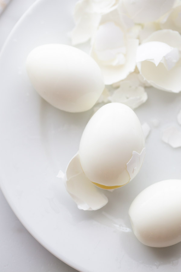 hard boiled eggs peeled on a white plate with peeled shells on the plate too